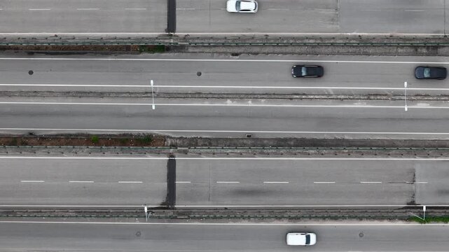 Aerial view of a car driving on a multi-lane highway with asphalt road markings and concrete dividers in Coimbra, Coimbra, Portugal.