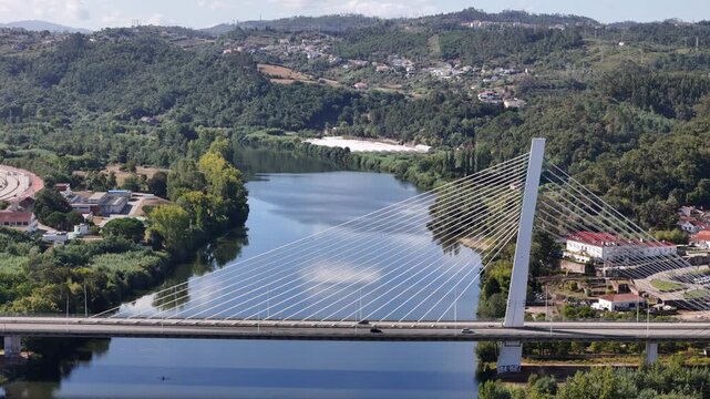 Aerial view of the modern cable-stayed Ponte Rainha Santa Isabel bridge spanning the Mondego River surrounded by lush green hills in Coimbra, Coimbra, Portugal.