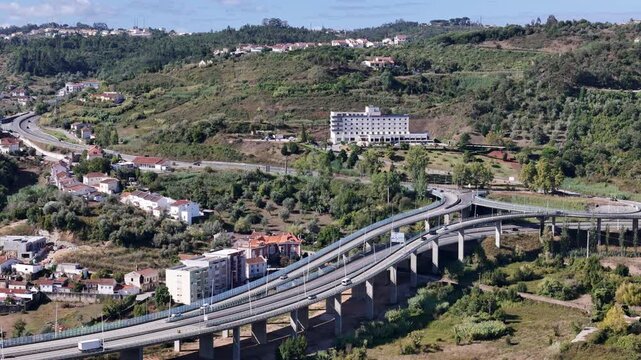 Aerial view of Ponte Rainha Santa Isabel bridge spanning the landscape with highway infrastructure, surrounding hills, and a hotel in Coimbra, Coimbra, Portugal.