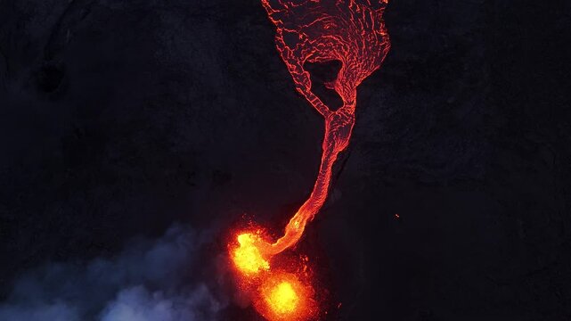 Aerial view of glowing lava flowing from a volcanic eruption over dark basaltic terrain with smoke plumes in Reykjavik, Reykjavikurborg, Iceland.