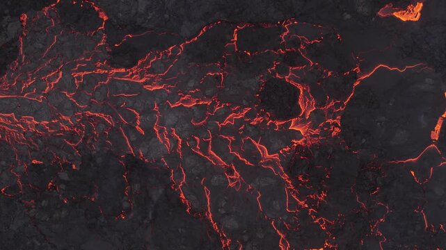 Aerial view of glowing red lava flowing through dark volcanic rock terrain in Reykjavik, Reykjavikurborg, Iceland.