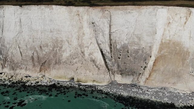 Drone Detail of Cliffs shot panning left to right over the White Cliffs of Dover, revealing the chalk coastline and turquoise sea in Kent, England, UK. Cinematic 4K video showing the landmark.