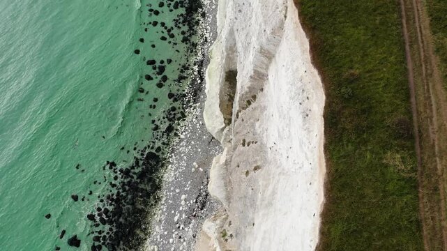 Cinematic top shot aerial of the famous White Cliffs of Dover and turquoise English Channel in Kent, England, UK. Panoramic drone footage of the iconic chalk coastline on a bright sunny day. 4K