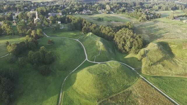 Aerial view of the historic Kernave archaeological site with its iconic green mounds, winding footpaths, and surrounding lush landscape in Kernave, Vilnius County, Lithuania.