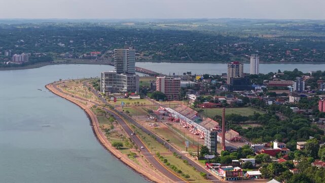 Aerial view of Posadas riverside promenade with urban coastal landscape and bridge in background.