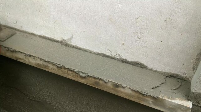 Fresh wet cement mortar applied to a concrete wall surface during construction.