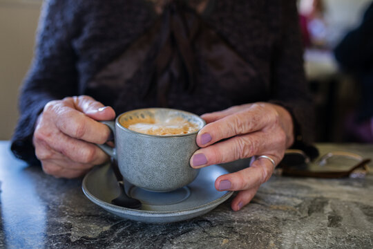 senior woman with flat white coffee in a cafe