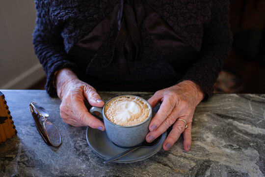 senior woman with flat white coffee in a cafe