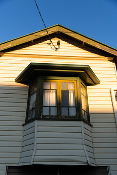 late afternoon light hitting the facade and bay window of an old timber house