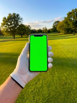 Hand holding smartphone on golf course with green screen