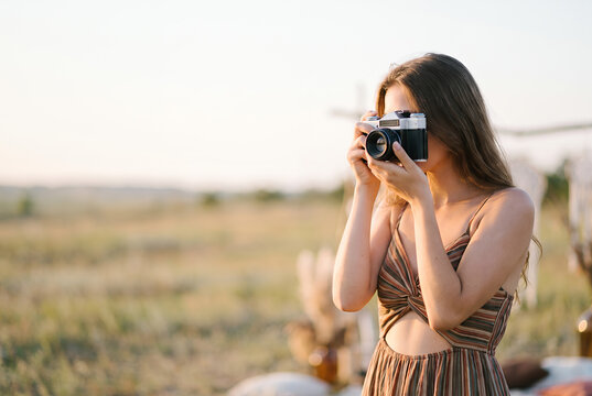 Young woman photographer holding vintage camera in rural field