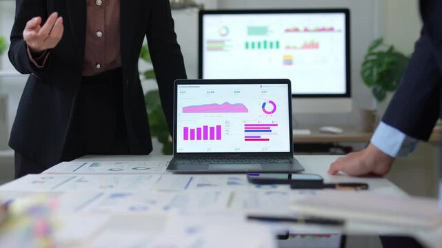 Business colleagues analyzing financial data charts and graphs during a corporate meeting in the office with a laptop