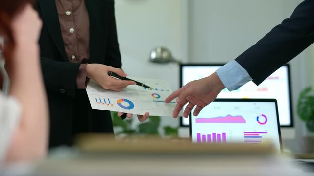 Business team analyzing financial data charts during a corporate meeting with documents and laptop statistics