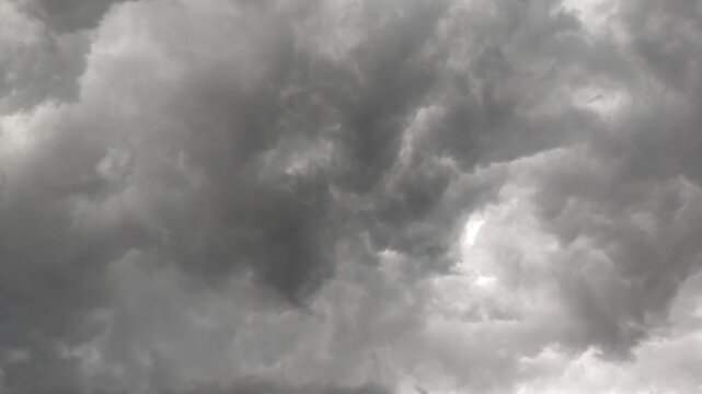 Dramatic dark storm clouds filling the sky before a heavy rainfall, creating an ominous and powerful weather atmosphere in a moody grayscale landscape