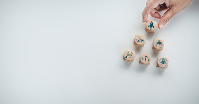 Business person hand placing wooden block with rocket icon on top of growth hacking strategy pyramid structure, concept of startup business growth, innovation, data analysis, and marketing strategy.
