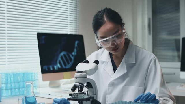 Asian scientist using a microscope for genetic research and analyzing a dna sample in a modern science laboratory