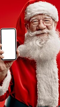Santa Claus smiles warmly, holding a blank smartphone. His red suit and white beard stand out against the vibrant red background. He appears cheerful, engaging, and friendly
