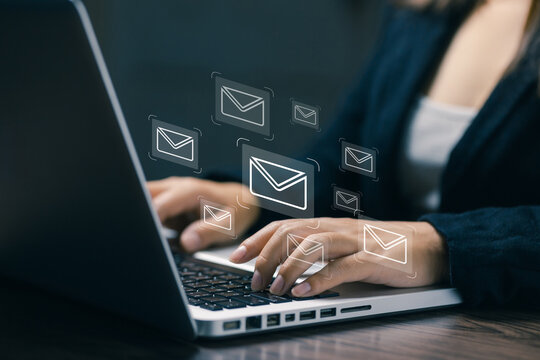 Business professional typing on laptop with floating email icons, representing digital communication, online messaging, business correspondence, customer contact, marketing, and remote work.
