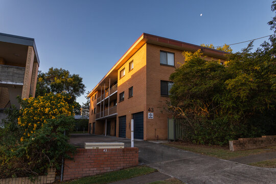 Streetview of a three-story brick apartment building with a flat roof