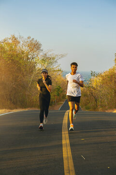 Silhouette of couple running together on road with sunset background.. Couple, fit runners fitness runners jogging together during outdoor workout.