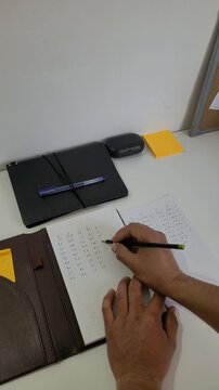A person writing in their planner, focused on their projects and jotting down numbers