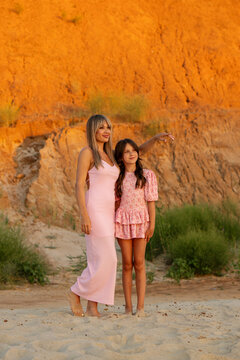 Mother Pointing Into Distance With Daughter Outdoors