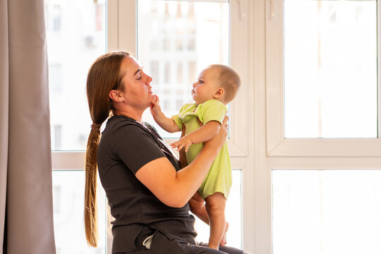 Baby Boy Touches Mother&rsquo;s Chin During Playful Window Moment