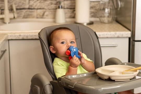 Baby Boy Bites Airplane Toy During Kitchen Mealtime