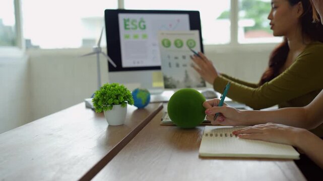 Businesswomen discussing esg corporate social responsibility and environmental sustainability in a modern green office meeting