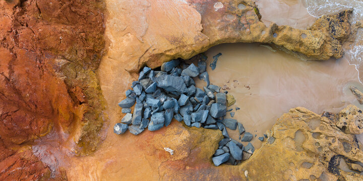 Aerial view of coastal rock formation with colour contrasts