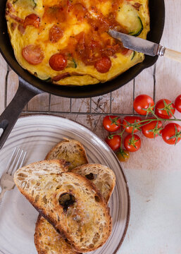 Golden omelette in cast-iron skillet with two slices of artisan toasted bread on the side