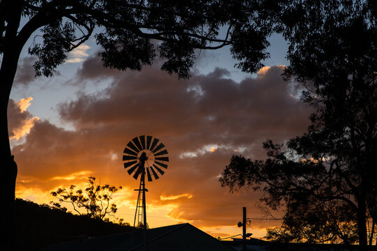 Classic windmill stands tall in silhouette at sunset