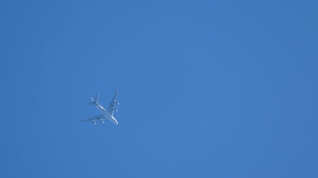 White Commercial Jet Flying High in Clear Blue Sky