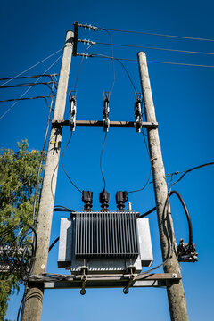 Pole-Mounted Electrical Distribution Transformer Against a Clear Blue Sky