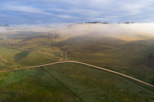 Morning mist drifting over rolling hills and winding country road in Australia