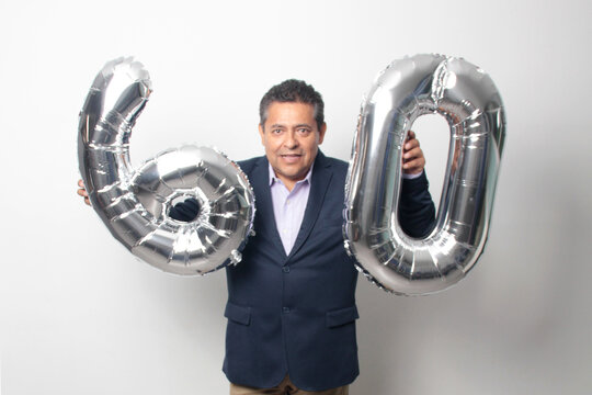 60-year-old Latino man with a dark skin displays 60 shaped balloons to celebrate his birthday and his entry into his old age