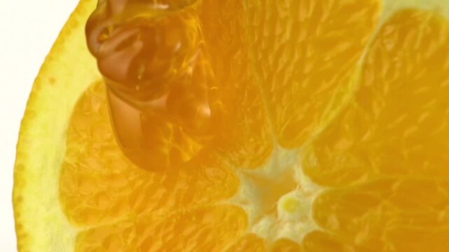 Pouring sweet golden honey or syrup onto juicy orange slice close up view