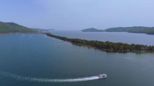 Speedboat leaving a sweeping wake beside Amanohashidate in Kyoto, Japan