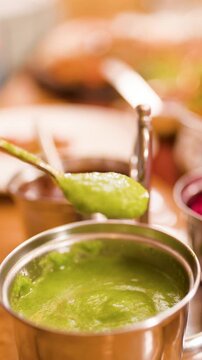 Spoon Dipping into Green Mint Chutney at Indian Restaurant