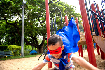 Child in a red mask and blue cape playing at a playground slide. © Rawpixel.com