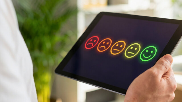 Person selecting emoji rating on tablet screen for customer satisfaction survey, representing feedback evaluation and service quality assessment