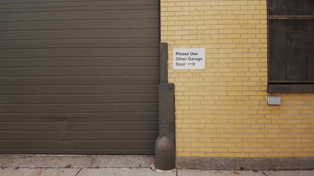 Static view shows sign directing drivers to another garage door on brick wall