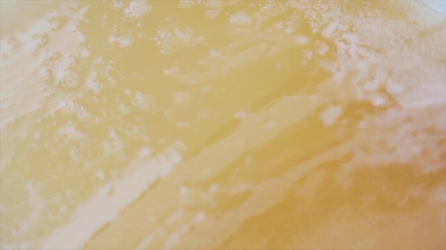 Extreme close view shows golden beer sloshing with swirling foam and bubbles