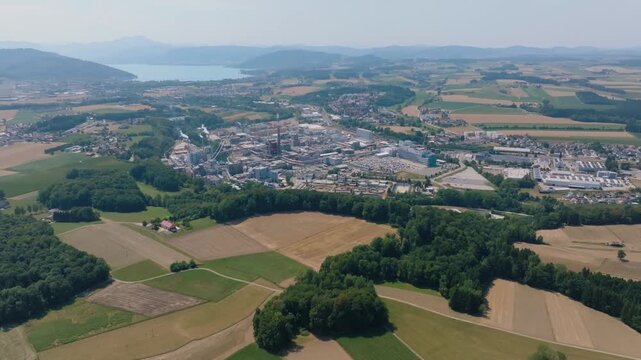 Stunning aerial panorama showing the Lenzing Plastics manufacturing plant, an industrial complex surrounded by lush green countryside and a lake