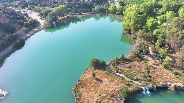 Aerial above hardening calcium deposits forming massive natural rock walls across the valley floor, holding back water to create step-like, cascading lagoons. Ruidera Lagoons Spain.