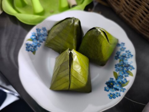 Traditional steamed snacks wrapped in banana leaves on a floral plate