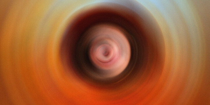Abstract radial blur background with warm brown and orange tones creating a swirling visual effect.