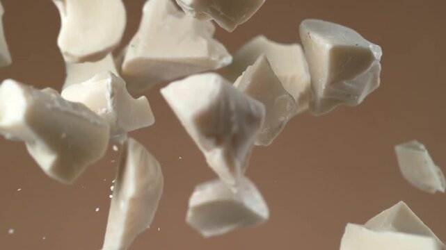 White chocolate chunks flying in slow motion close up