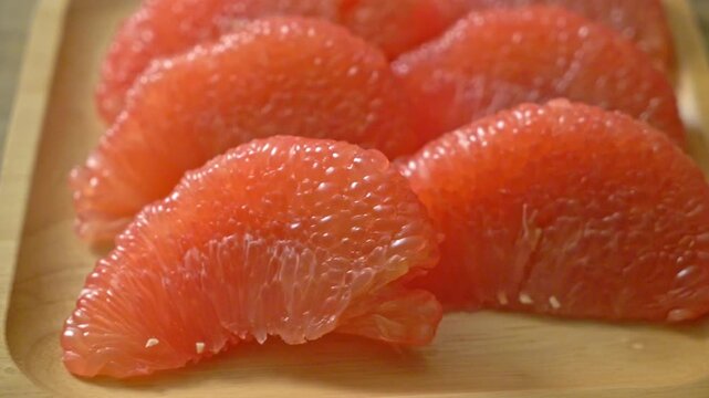 Fresh peeled pomelo segments arranged on wooden plate for healthy nutrition.