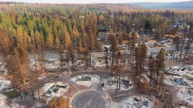 Spokane wildfire damage shown in a sweeping pan across the Rifle Club area, revealing rows of burned properties, blackened trees and extensive residential loss from the 2026 fire.